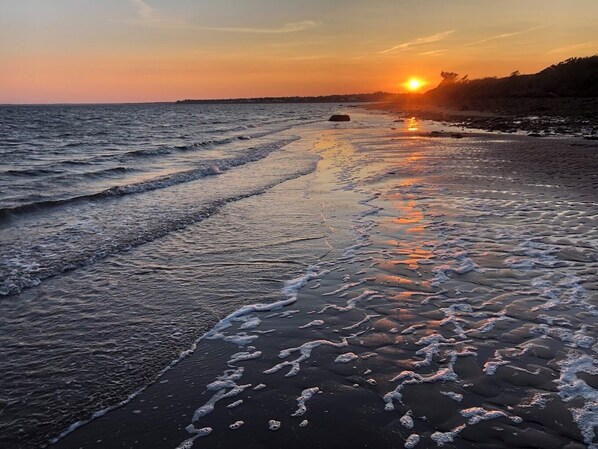 Una playa al atardecer con olas llegando a la orilla.