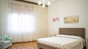 Una camera da letto con un letto, un comodino, una lampada, una sedia e un lampadario.