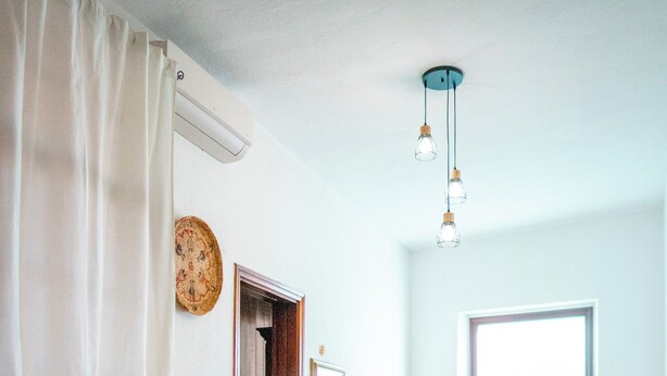 Una stanza con piastrelle a motivi, un tavolo di legno con un vaso, una porta e un lampadario.