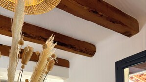 A modern kitchen with a wooden dining table, bar stools, and a vase with dried plants. - Beautiful detached villa on one level with pool, view and charging station! (La Cadière-d'Azur)