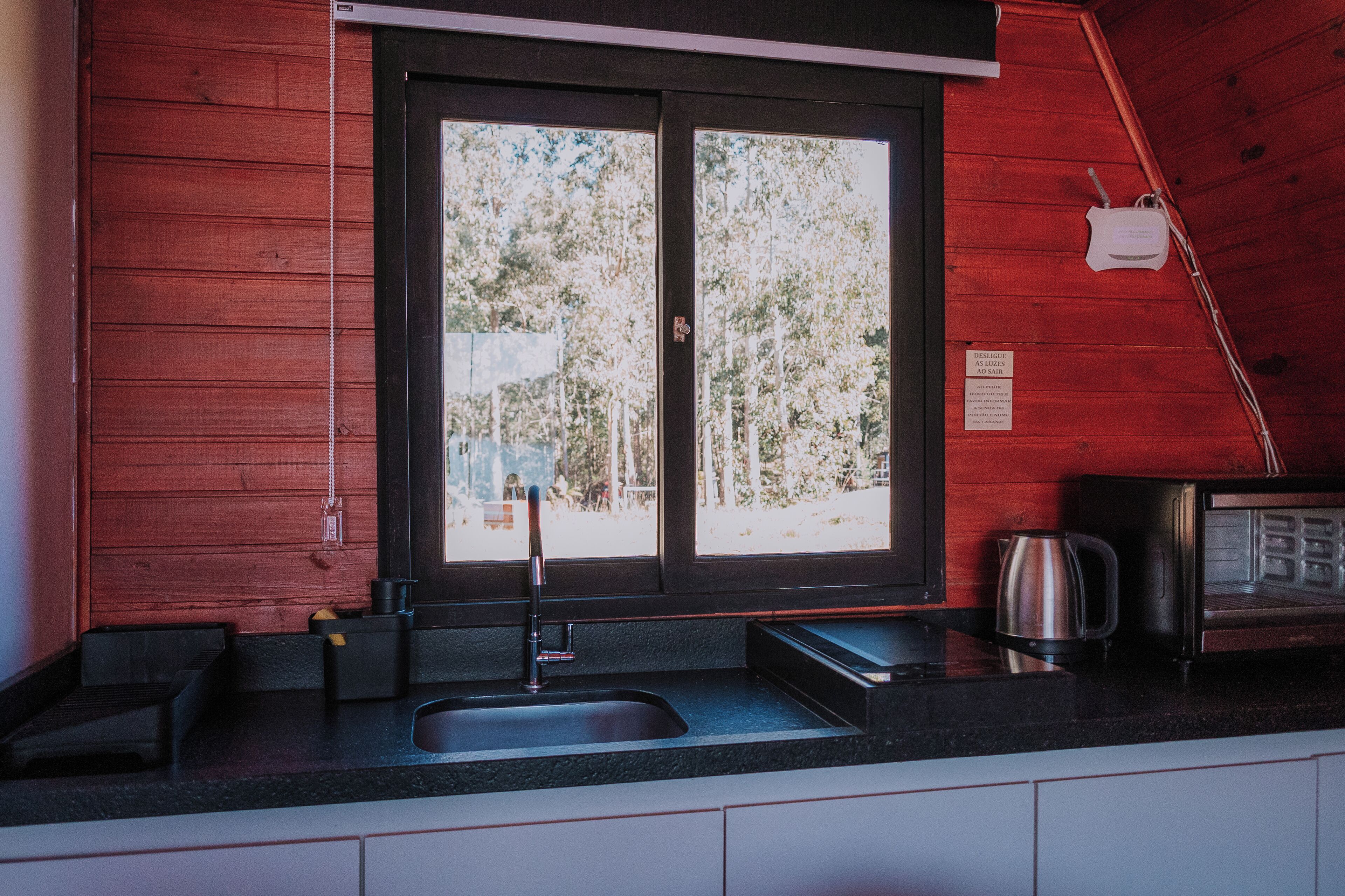 A kitchen with a sink, a kettle, and a microwave.