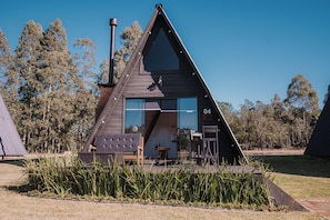 A modern A-frame cabin with a large glass door, a chimney, and a small porch area. - Vila Gramado (Gramado)