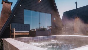 Un espace dédié à un bain à remous, avec un bord carrelé, un banc en bois et une chaise.