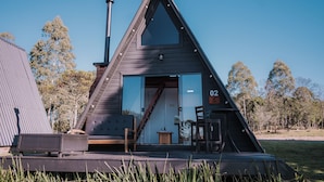 A triangular wooden cabin with a large window, a chimney, and a number '02' sign. - Vila Gramado (Gramado)