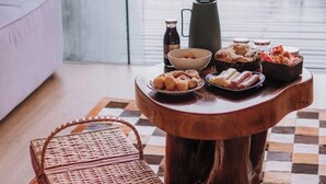 Une table en bois, un tapis à carreaux, un panier en osier et une variété de collations et de boissons.