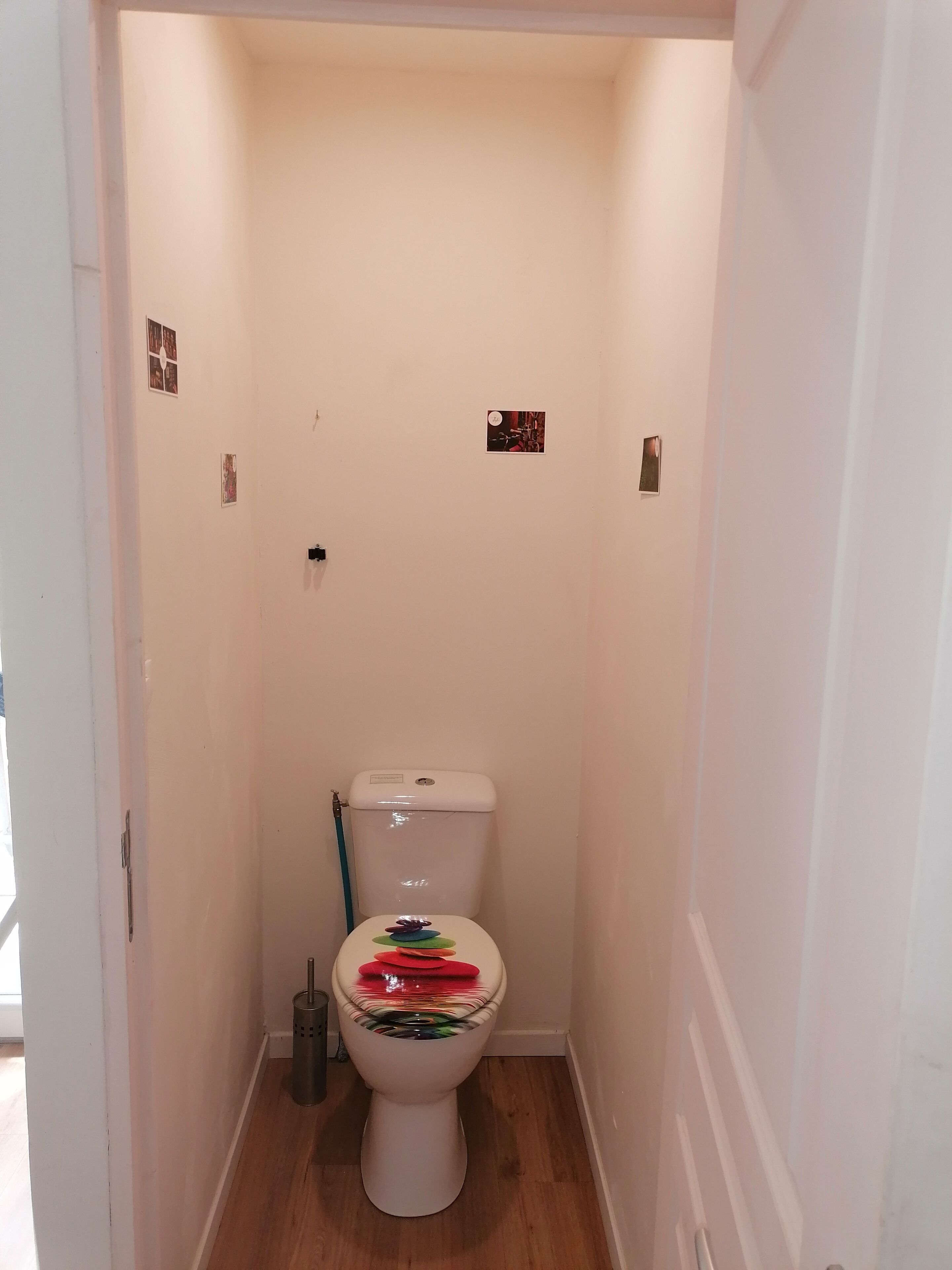 Ein kleines, schmales Badezimmer mit Toilette, Mülleimer und einem Lichtschalter an der Wand.