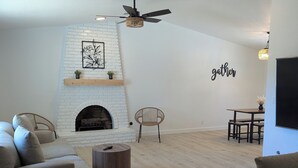 Un salon avec une cheminée, deux canapés, une table basse et un coin repas équipé d’un téléviseur.
