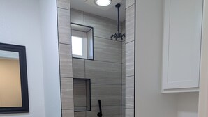 Une salle de bain avec douche, toilettes et un meuble-lavabo avec miroir.