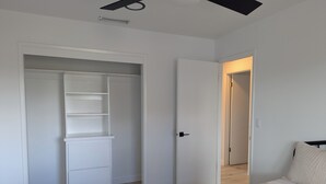 Une chambre à coucher comprenant un lit, une armoire et une porte donnant sur une autre pièce.