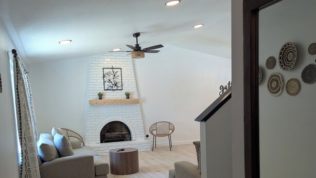 Un salon avec une cheminée, un canapé, une table basse et un ventilateur de plafond.