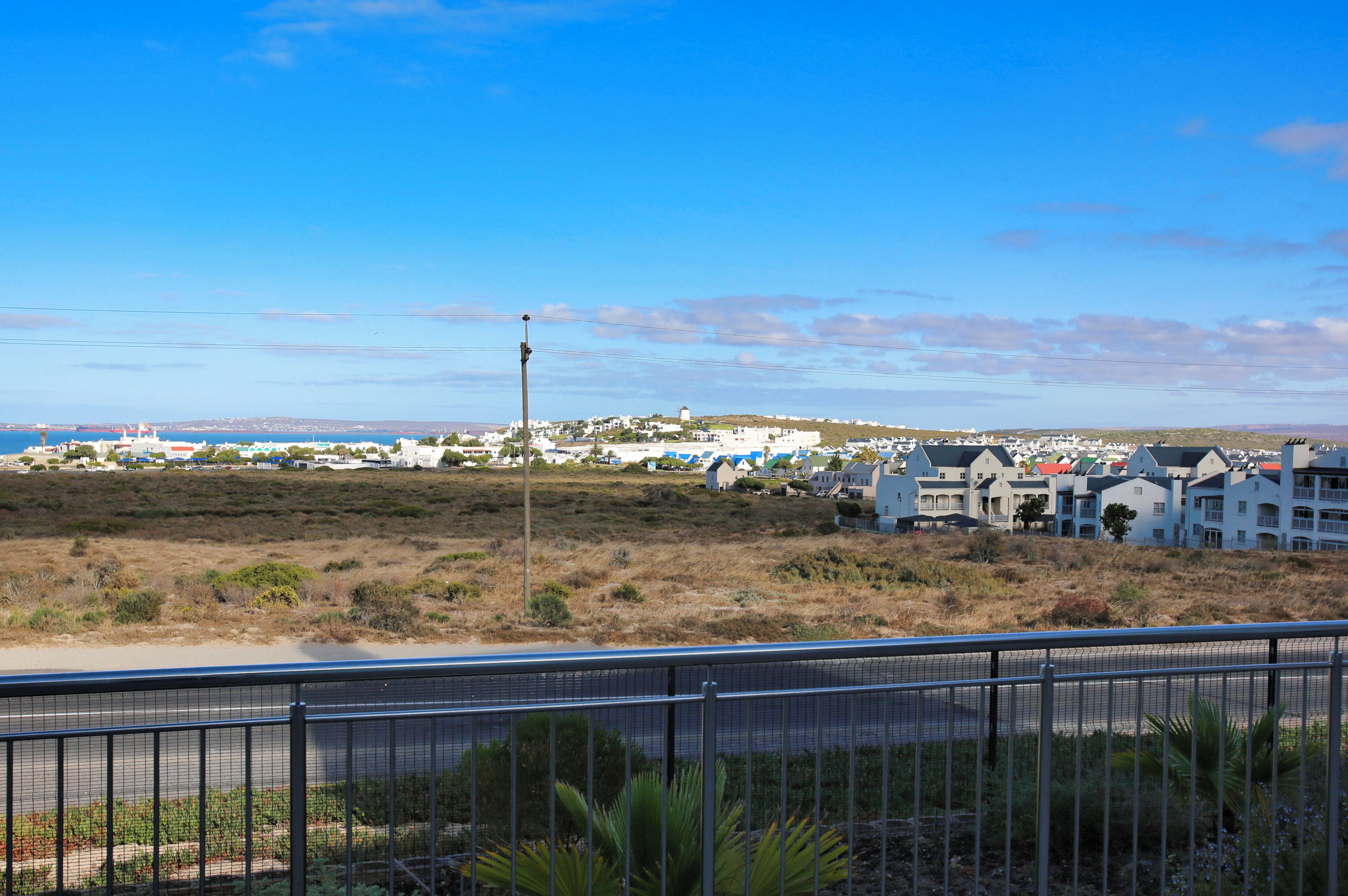 A coastal town with a prominent lighthouse, white buildings, and a clear view of the sea.