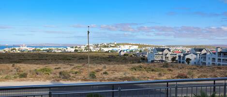 A coastal town with a prominent lighthouse, white buildings, and a clear view of the sea.