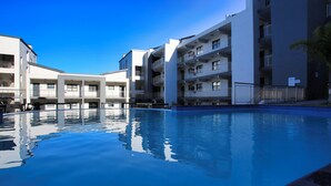 A swimming pool surrounded by modern multi-story buildings with balconies. - NIVICA Lifestyle Living 20, Langebaan 4-Sleeper (Langebaan)