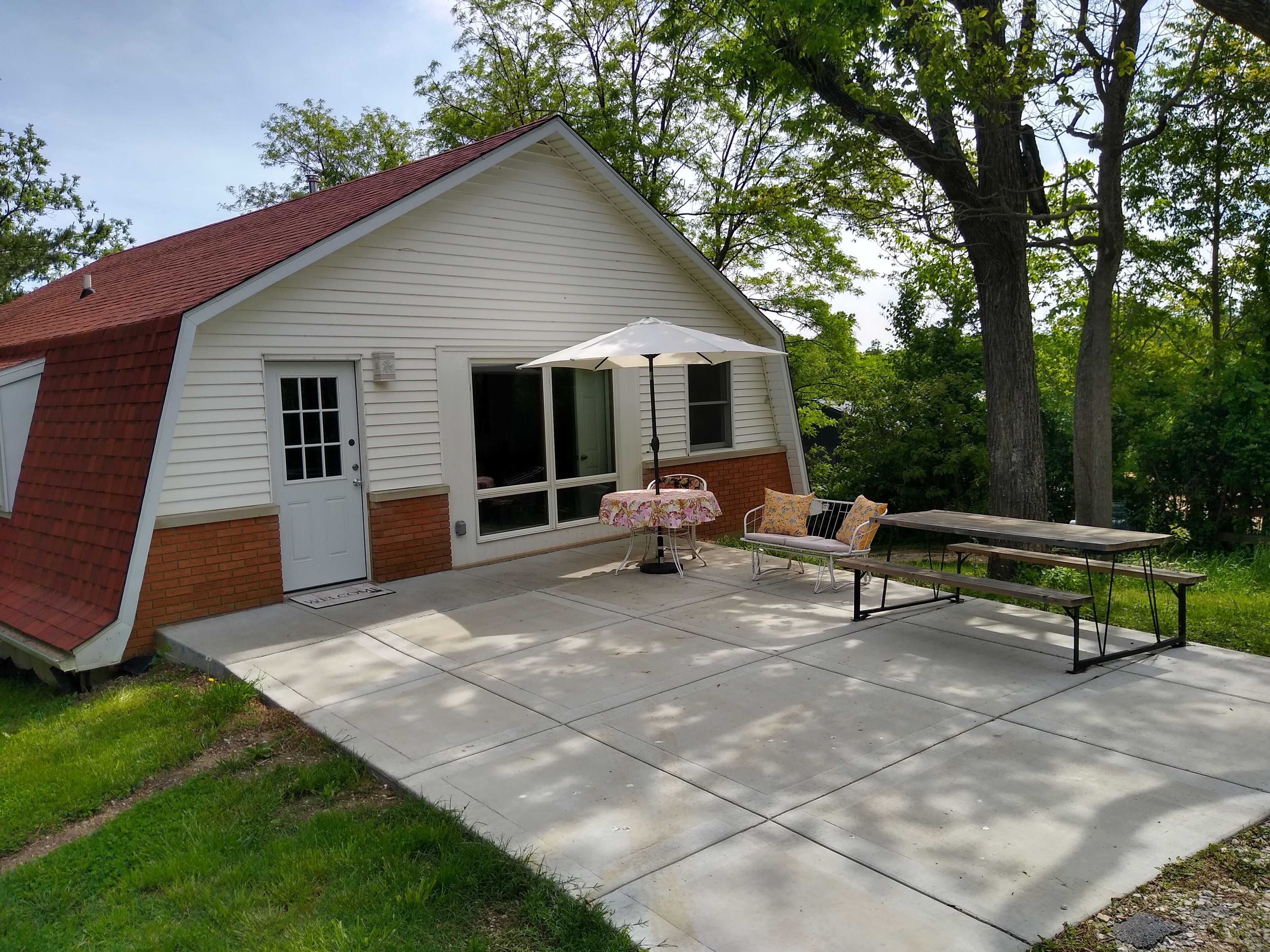Una casa con un patio, una mesa con sillas y una sombrilla.