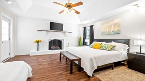 A bedroom with a bed, a bench, a fireplace, a TV, and a ceiling fan. - Spacious Lakefront Getaway for 9, Pet-Friendly 3BR/2BA Cottage + Free Boat Slip! (Buchanan)
