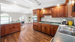 Une cuisine spacieuse avec des meubles en bois, un évier en acier inoxydable et un grand îlot central.