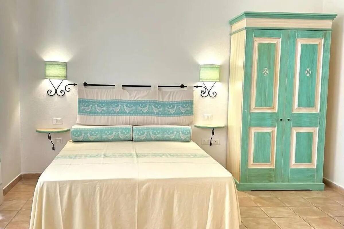 Ein Schlafzimmer mit einem Bett, zwei Nachttischlampen, einem Nachttisch und einem Kleiderschrank.