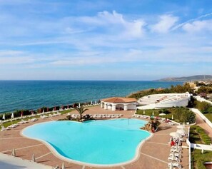 A resort with a large pool, lounge chairs, and a view of the sea. - Acqua di Mare Hotel e Resort (Sorso)