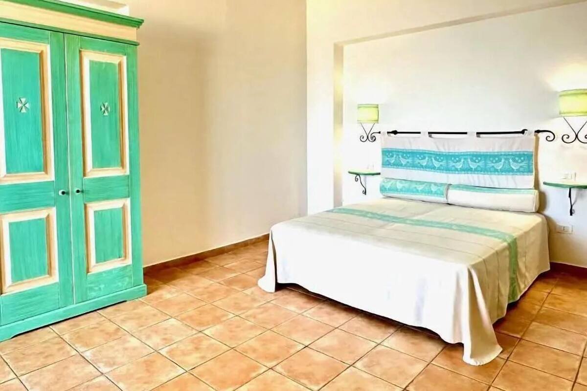 Ein Schlafzimmer mit einem Bett, einem grünen Schrank und einer Wandleuchte.
