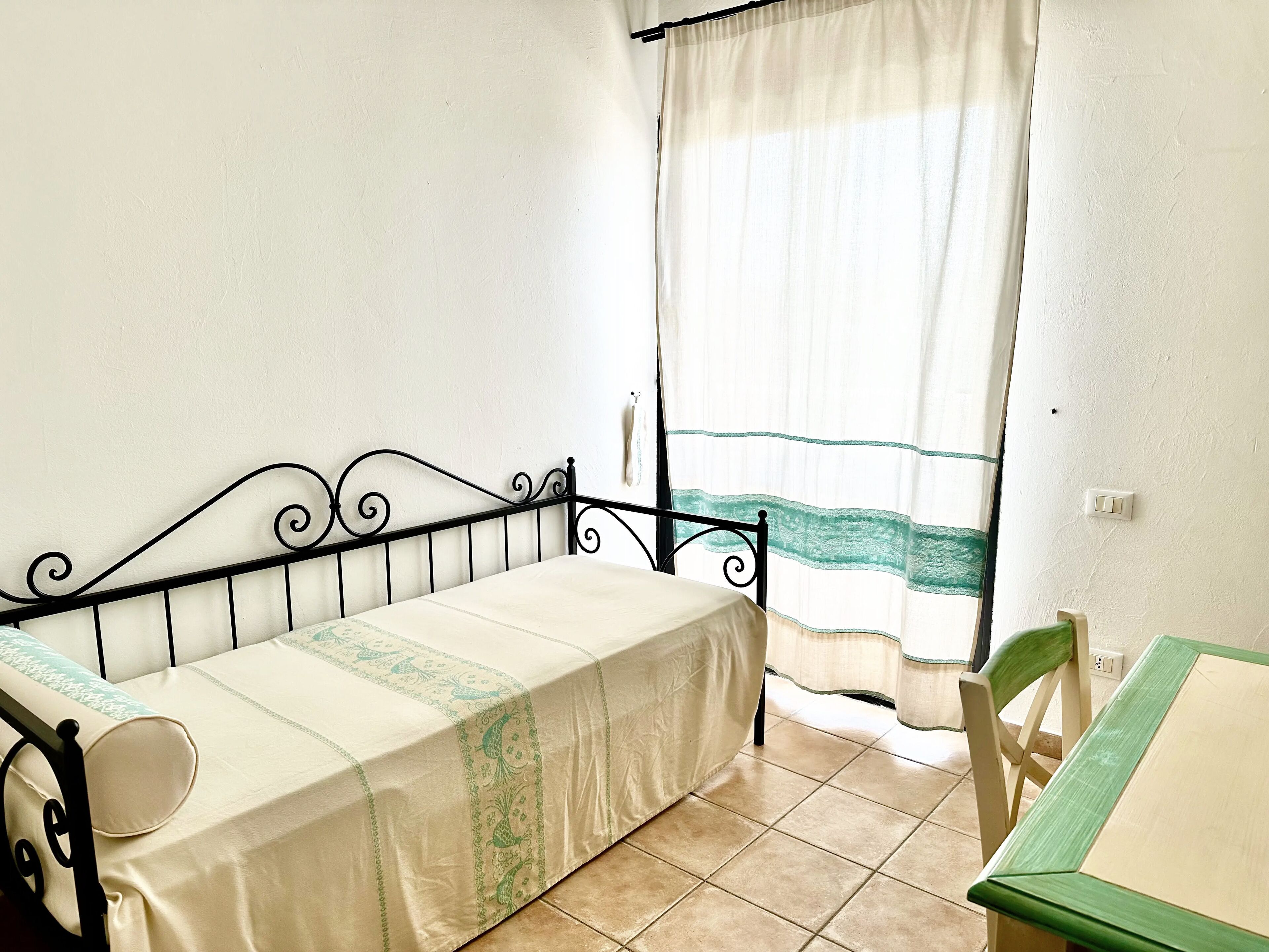 Une petite pièce simple, avec un lit, une chaise et une table.