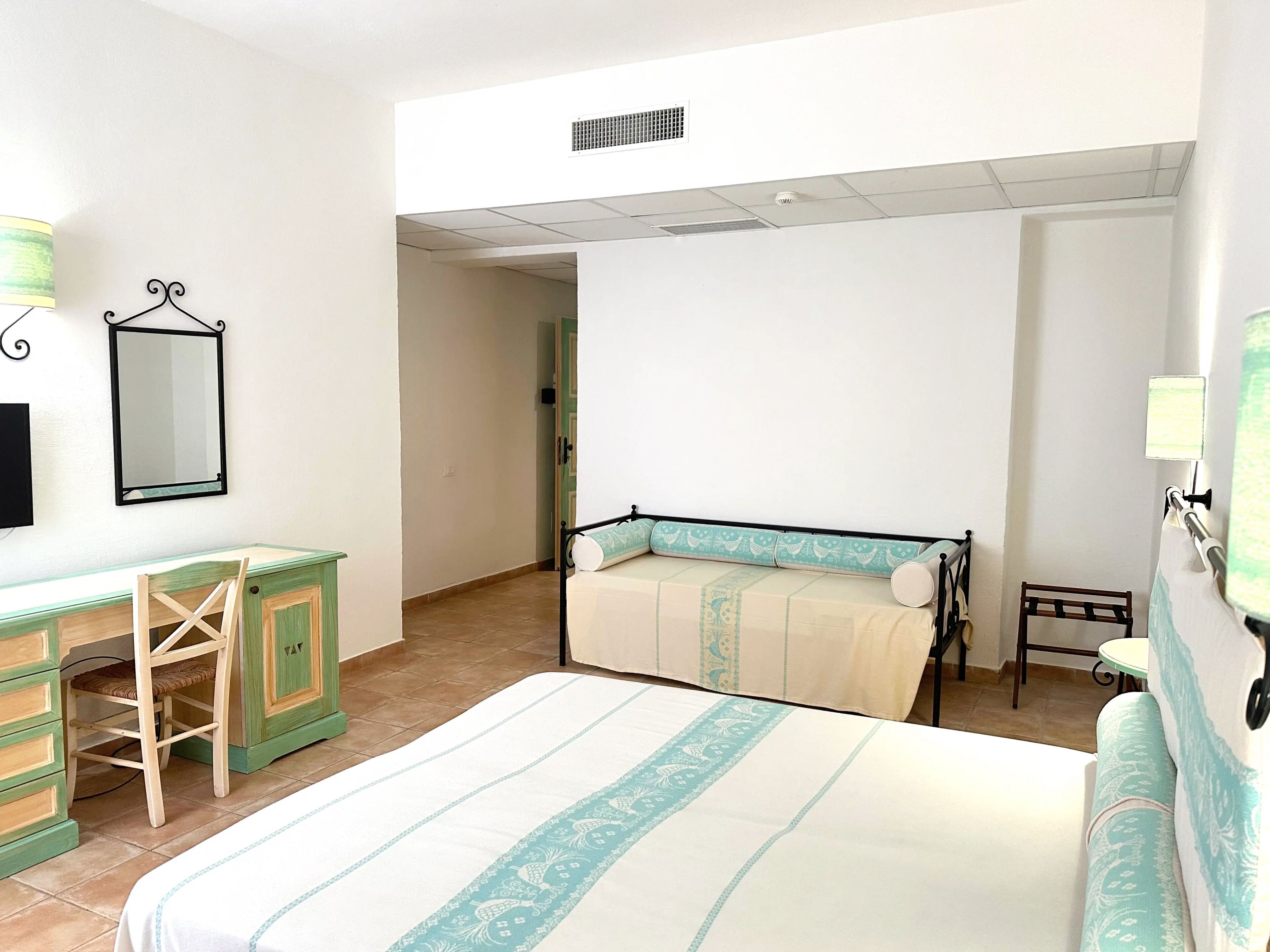 A bedroom with a bed, a desk, a chair, and a wardrobe.
