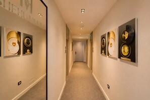 A hotel hallway with artwork on the walls, carpeted floors, and a door at the end. - Shehu Villa Ksamil (Ksamil)