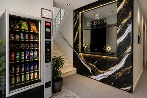 A vending machine with snacks and drinks, a reception desk with a marble design, and a staircase. - Shehu Villa Ksamil (Ksamil)