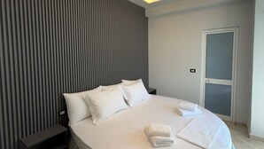 A modern bedroom with a circular bed, a slatted wall, and a ceiling light fixture. - Shehu Villa Ksamil (Ksamil)