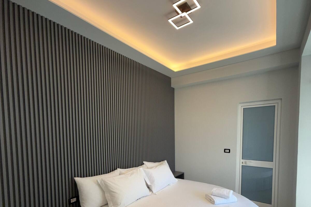 A modern bedroom with a circular bed, a slatted wall, and a ceiling light fixture.