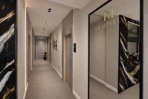A hallway with a marble wall, a sign for room 101, and a mirrored wall with a logo. - Shehu Villa Ksamil (Ksamil)
