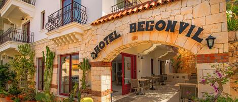A hotel entrance with a stone archway, outdoor seating area, and potted plants.