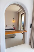 Un dormitorio con cama, mesita de noche, lámpara colgante y vistas al exterior a través de una ventana.
