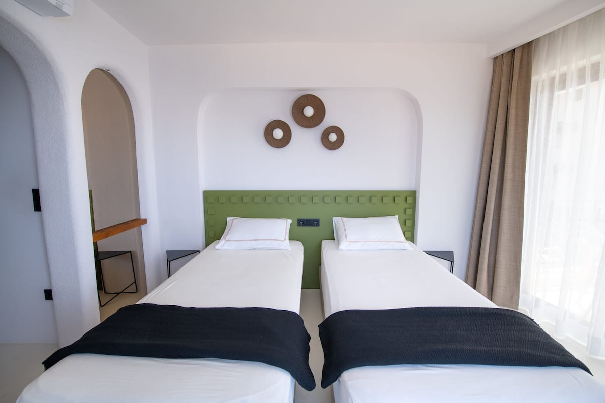 Una habitación de hotel con dos camas individuales, un cabecero verde y un reloj fijado a la pared.