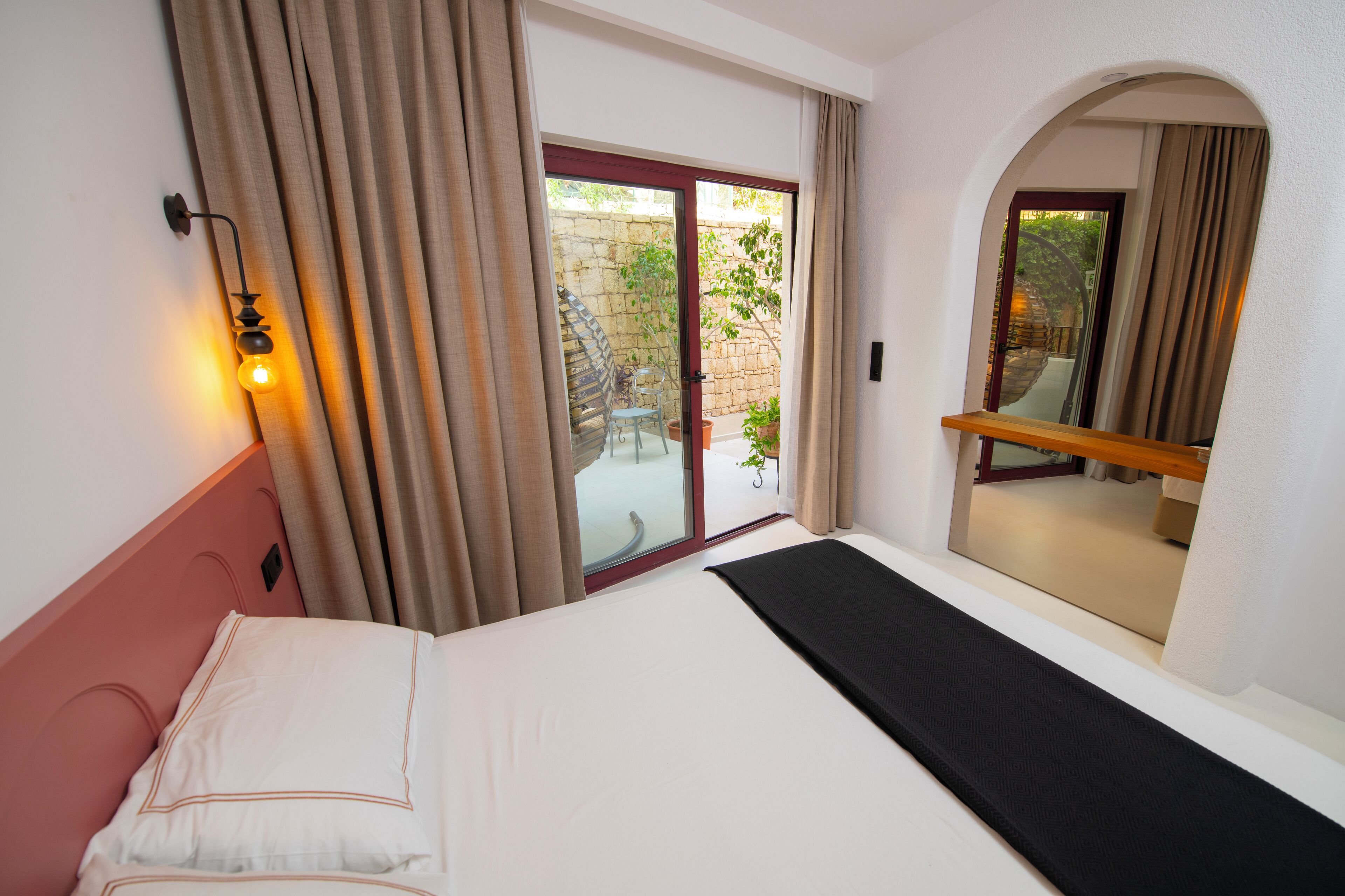 A hotel room with a bed, a sliding glass door to an outdoor area, and a small balcony.