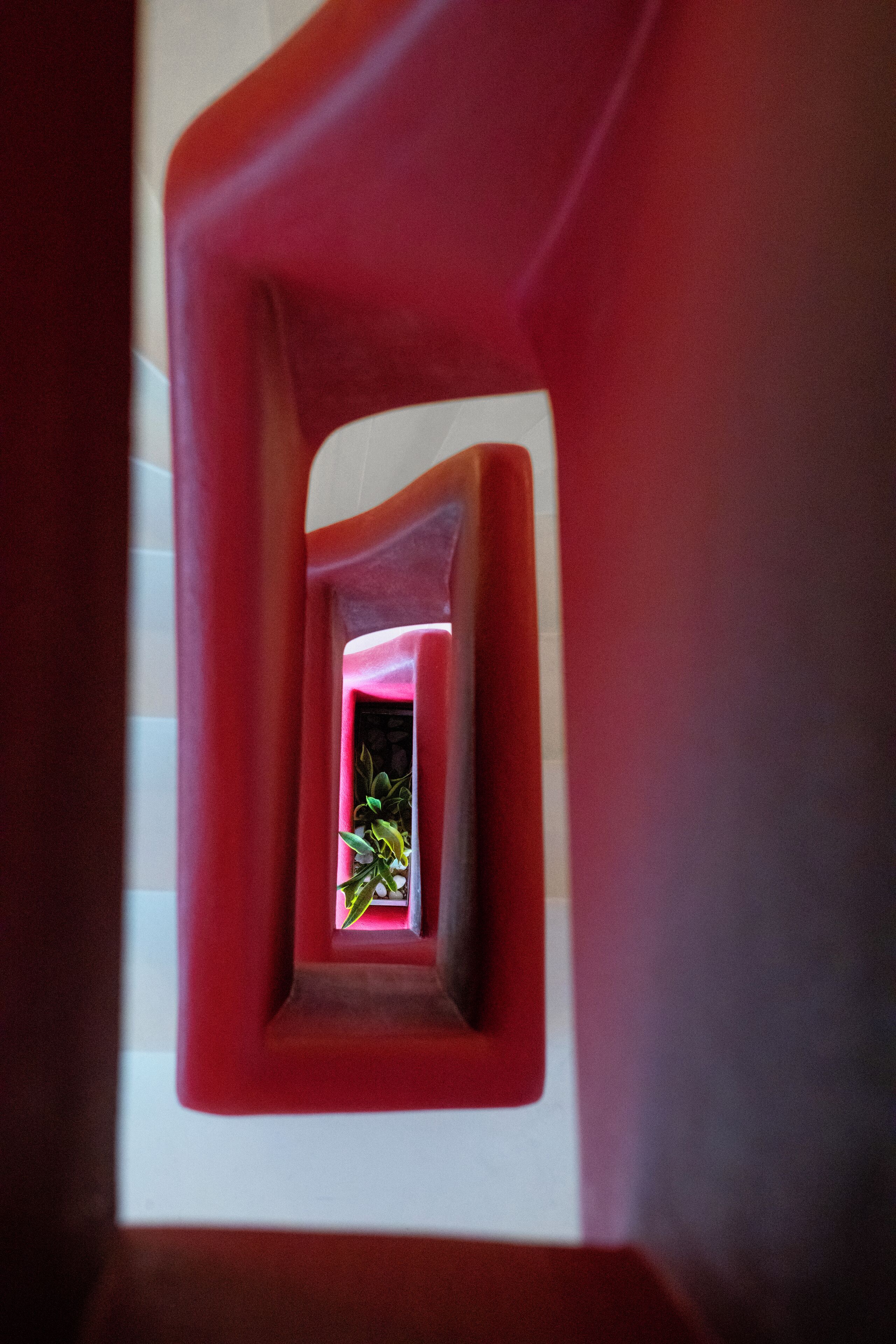 A narrow, red-framed corridor with a small plant visible at the end.