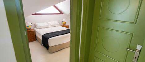 A bedroom with a bed, a nightstand, a lamp, and a window.