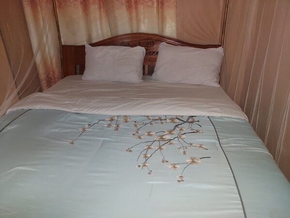 Ein Bett mit blumigem Überwurf und zwei Kissen.