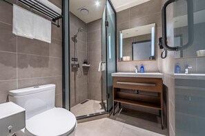 A modern bathroom with a toilet, shower, and sink area.