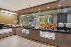 Eine moderne Frühstückstheke mit vielfältigen Speisen, einer Kaffeemaschine und einem Spiegel, der das Interieur widerspiegelt.