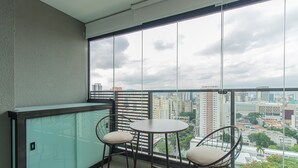 A balcony with two chairs and a small table, overlooking a cityscape with buildings and trees. - Modern Studio Near Allianz Parque Sp-p1610a (São Paulo)