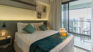 A hotel room with a large bed, a balcony with a view of the city, and a small table with a chair. - Modern Studio Near Allianz Parque Sp-p1610a (São Paulo)