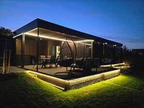 Relax in the covered patio area with a dining table, chairs, and a hanging chair.