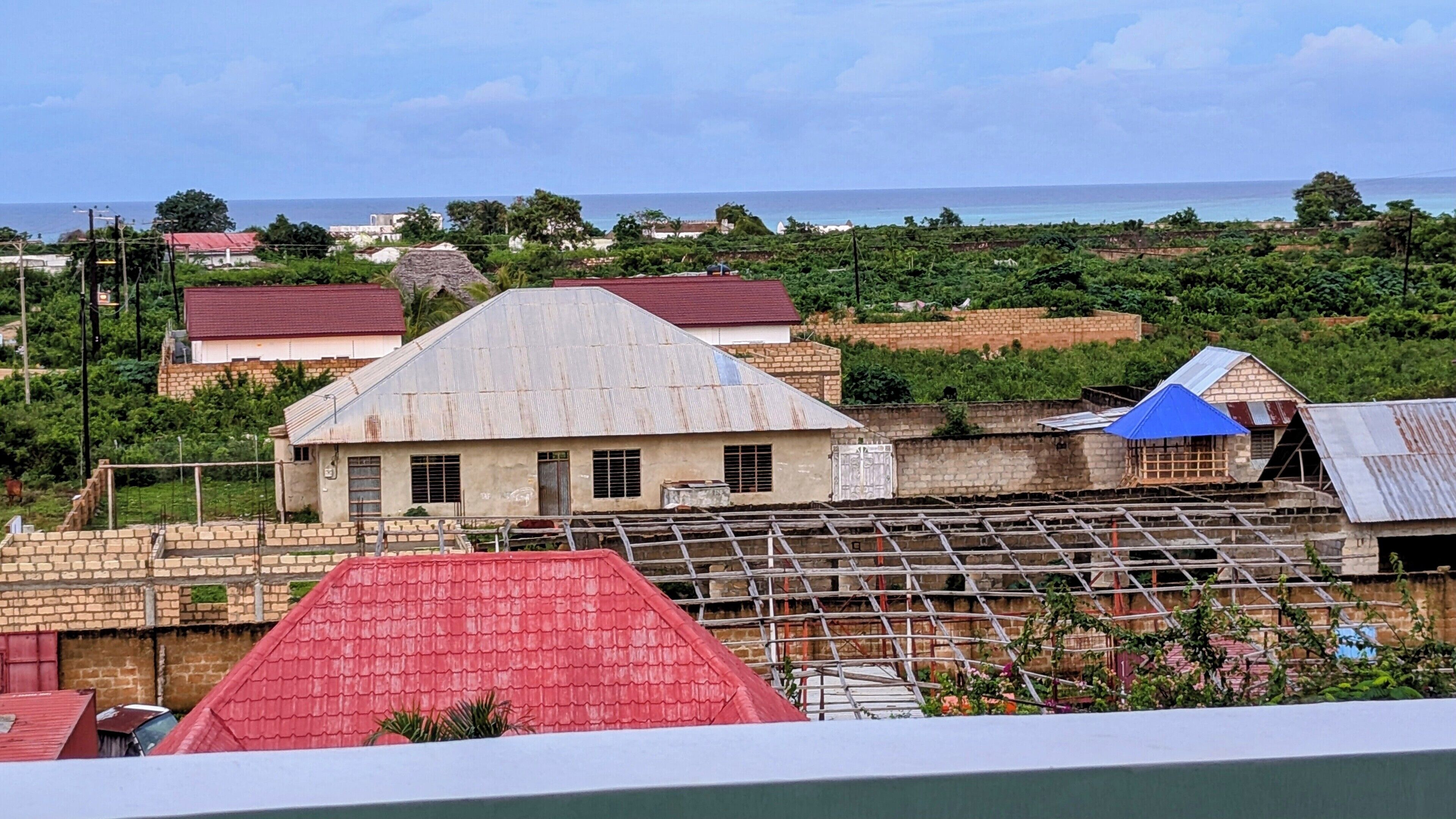 Un village côtier avec des maisons traditionnelles, un grand bâtiment doté d’un toit rouge et une vue sur la mer.