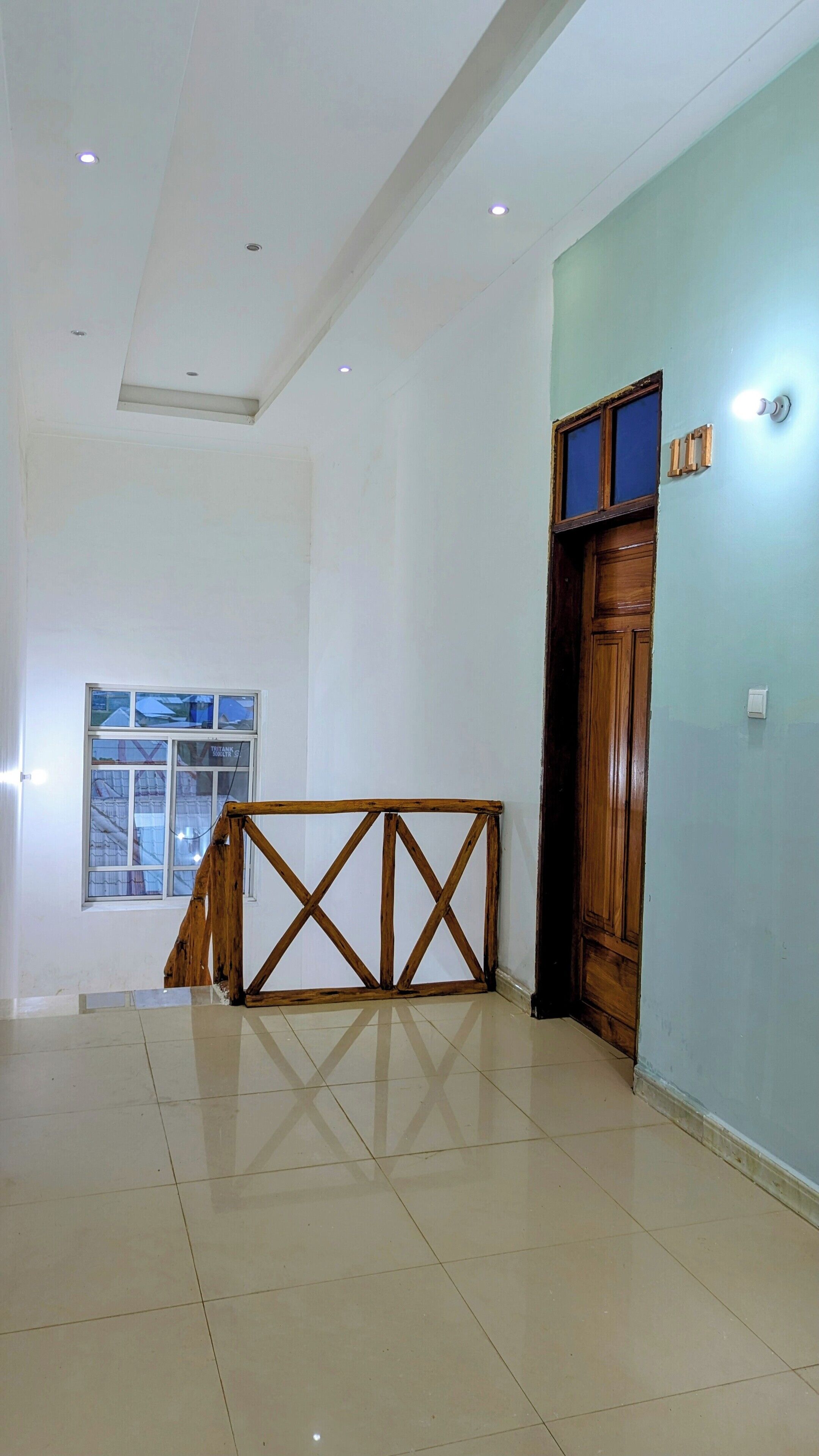 A spacious room with a wooden railing, a large window, and a door with a wooden frame.