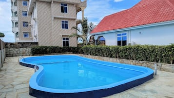 Una piscina al aire libre, sombrillas, sillones reclinables de piscina