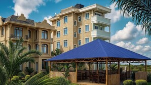 A multi-story building with a covered outdoor seating area and lush landscaping. - Crown View Hotel (Nungwi)