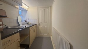 A compact kitchen with a sink, countertop, and cabinets.