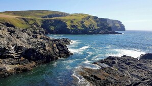 A coastal landscape with rocky cliffs and a clear view of the ocean.