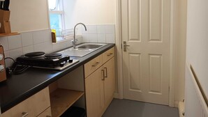 A compact kitchen with a sink, stove, and wooden cabinets.