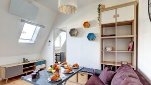 A modern kitchen with a dining table set for breakfast, a sofa, and a bookshelf. - Champs-Élysées - 1BR (Paris)